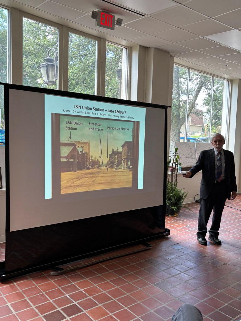 Presentation slide showing an old image of L&N Union Station from the late 1800s, featuring streetcars, tracks, and a person on a bicycle.